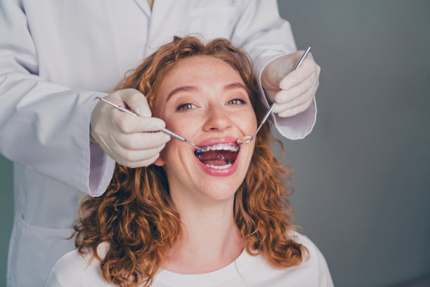 专业牙医检查患者牙齿的照片，积极的女性在新牙科诊所就医。图片下载