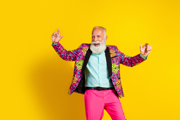 穿着华丽服装的积极快乐老年舞者在黄色背景下享受舞蹈乐趣的照片图片下载