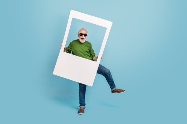 兴奋无忧的人在蓝色背景下手持纸质相册卡片跳舞的全身照片图片下载