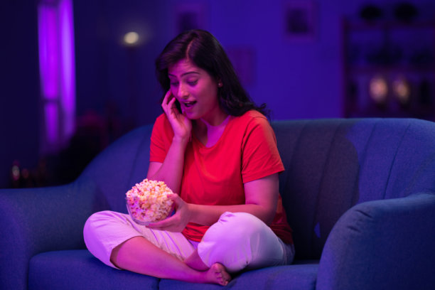 美丽的女人在家沙发上夜晚看电视的照片图片下载