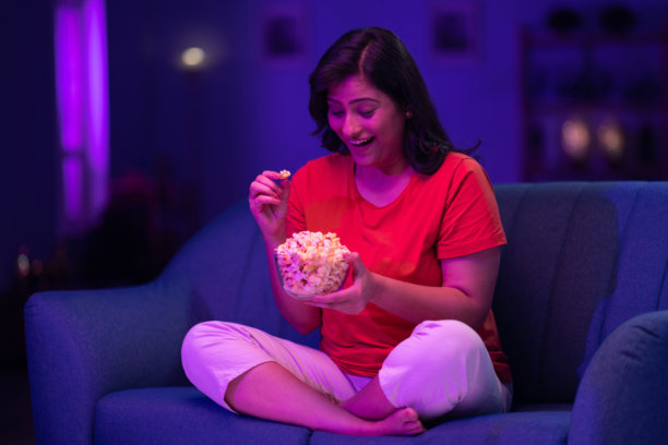 美丽的女人在家沙发上夜晚看电视的照片图片下载