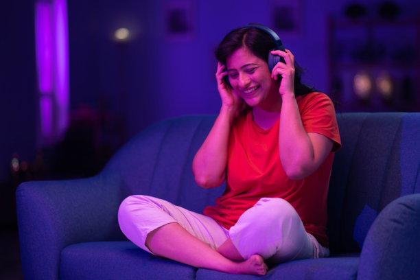 美丽的女人戴着耳机听音乐，举起双手唱歌跳舞的照片图片下载