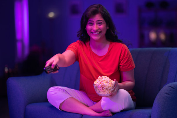 美丽的女人在家沙发上夜晚看电视的照片图片下载