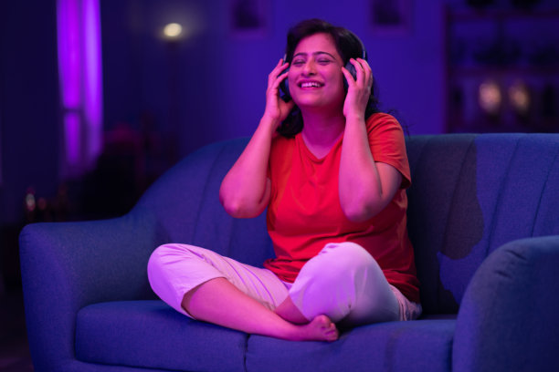 美丽的女人戴着耳机听音乐，举起双手唱歌跳舞的照片图片下载