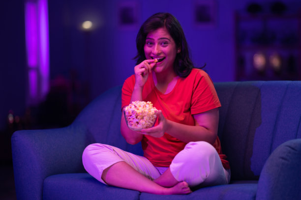 美丽的女人在家沙发上夜晚看电视的照片图片下载