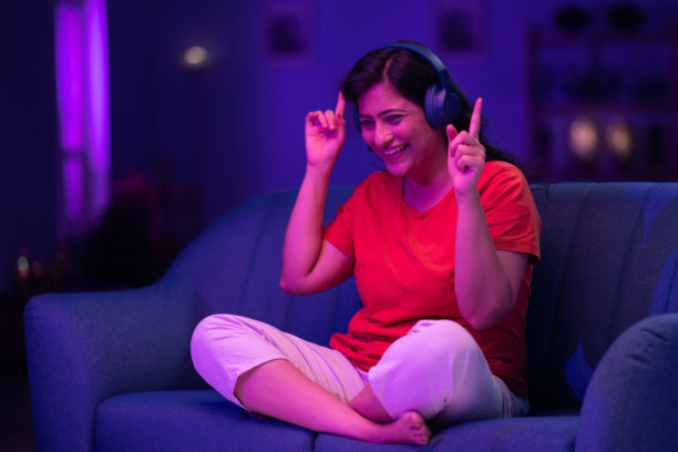 美丽的女人戴着耳机听音乐，举起双手唱歌跳舞的照片图片下载