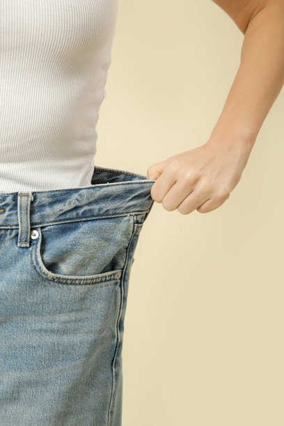 年轻的高加索女性在减肥后穿着宽松牛仔裤的工作室照片图片下载