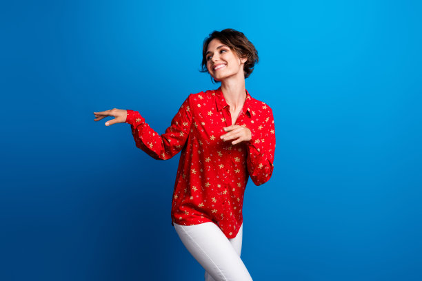 穿着红色圣诞节衬衫的漂亮年轻女性在蓝色背景下跳舞的照片图片下载