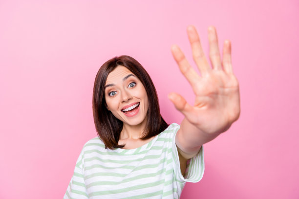 年轻积极的女孩在粉色背景下展示高五手势，兴奋有趣的特写照片图片下载