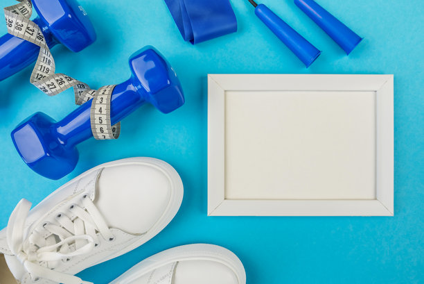 健身和运动的概念。白色运动鞋、空白框架、跳绳和蓝色哑铃的俯视照片，背景为纯色浅蓝色，留有空白空间。图片下载