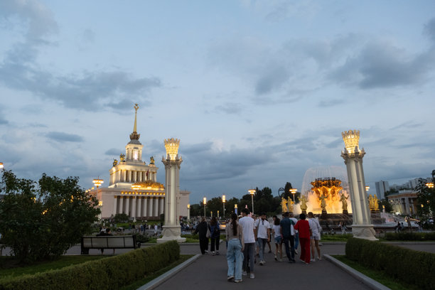 晚间的VDNH展览中心照片，展现了标志性的中央展馆和金色喷泉在柔和灯光下的壮丽景观。图片下载