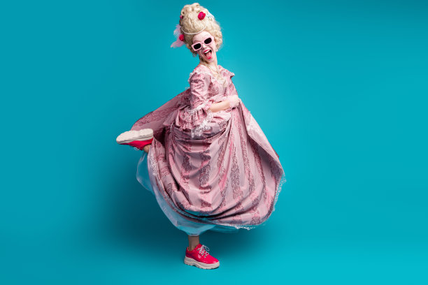 年轻女性穿着文艺复兴女王服装在青色背景下尽情舞蹈的全身照片图片下载