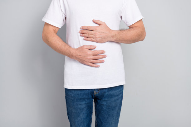 老年男子双手抱住腹部，面露痛苦，健康饮食概念，银色背景下的特写照片图片下载