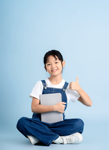 一位亚洲女孩在蓝色背景下学习并摆姿势的图片图片下载