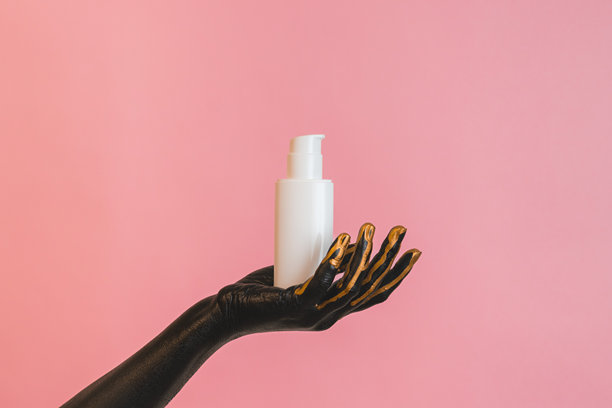 手中拿着化妆玻璃管，手上涂有黑色颜料。展示奢华护肤产品。适合您的设计的图片。图片下载