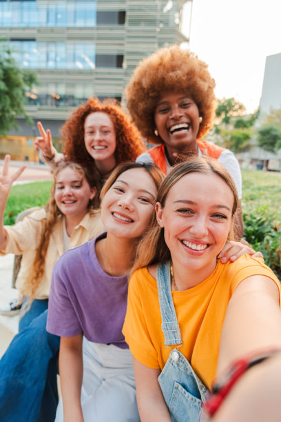 年轻的多种族女性群体竖着拍摄自拍，使用智能手机分享至社交媒体。青少年女孩们在周末享受乐趣，微笑着拍摄留念照片。图片下载
