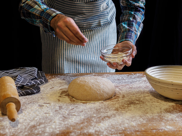 面包师制作手工面包。烘焙工具。黑色背景。黑白照片。图片下载