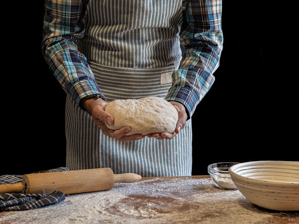 面包师制作手工面包。烘焙工具。黑色背景。黑白照片。图片下载