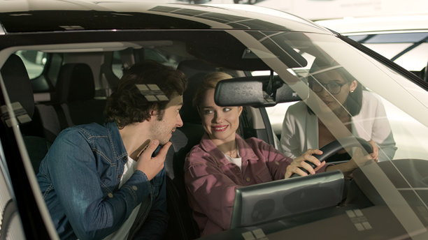 在现代汽车经销商处，顾客在购买前仔细检查一辆流线型的汽车。这张照片传达了舒适与科技的氛围，吸引了当今的汽车爱好者。图片下载