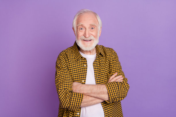 帅气的爷爷照片肖像，灰色头发，因好消息而感到惊喜，穿着时尚的黄色格子衬衫，背景为淡紫色。图片下载