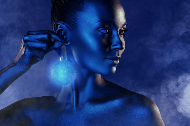 快乐的美国女孩佩戴新年树形耳环，手持圣诞节装饰球，背景为涂鸦风格的合成照片拼贴。图片下载