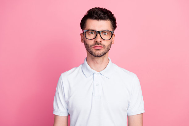 年轻吸引人的严肃胡须男士，戴着眼镜，作为企业家，独自站在明亮的粉色背景前的特写照片图片下载