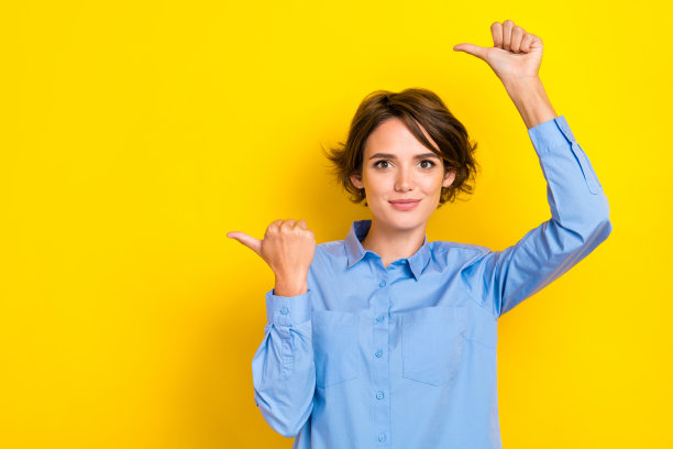 年轻可爱的女孩办公室经理的肖像照片，指向空白空间，推荐未来的职位，背景为明亮的黄色。图片下载