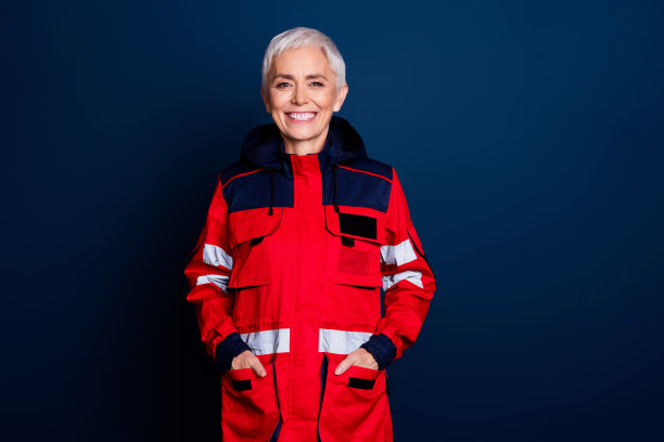 穿着制服的救护医生，面带愉快微笑，双手插口袋，站在深蓝色背景前的可爱老年女性照片图片下载