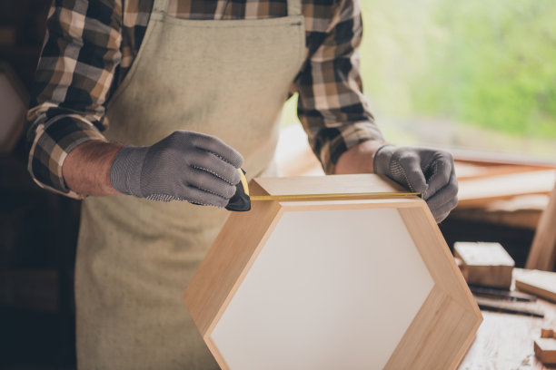 裁剪的照片，木匠在室内车库用卷尺测量木材。图片下载