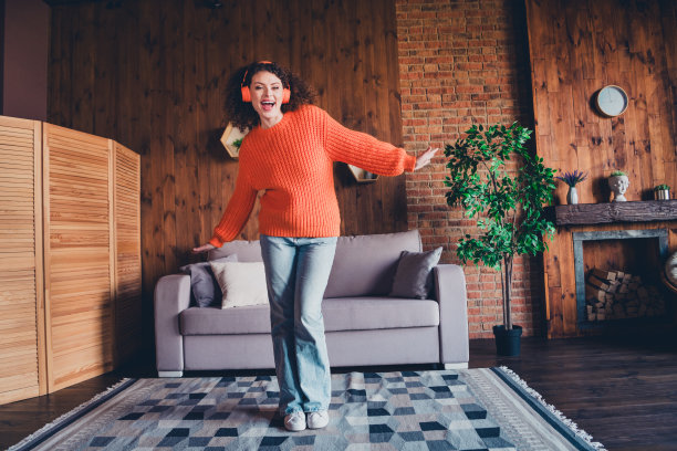 年轻漂亮的女子在公寓内的阁楼里听音乐跳舞的全身照片图片下载