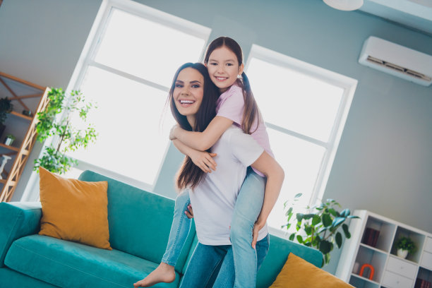 快乐的家庭照片，妈妈和女儿在舒适的客厅里一起度过愉快的时光，心情愉悦。图片下载