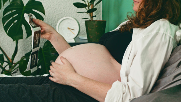 孕妇在舒适的客厅沙发上放松，查看超声波照片图片下载
