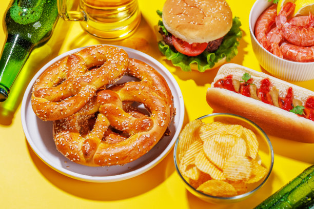 一张生动的照片，展示了一杯啤酒，周围是各种小吃和快餐。图片下载