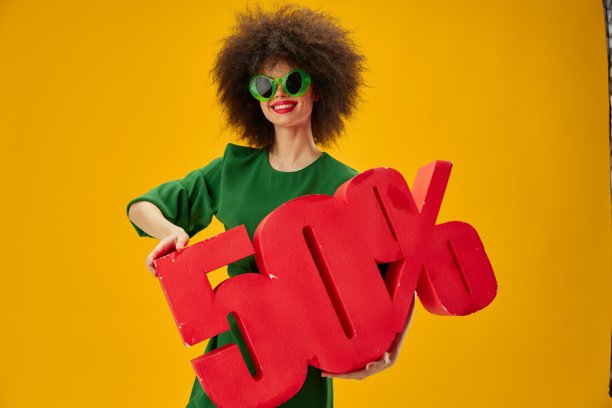 美丽时尚的女孩，卷发，绿色连衣裙，五折优惠，黄色背景图片下载