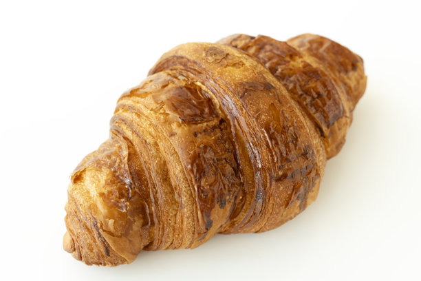 新鲜出炉的可颂面包，孤立在白色背景上。单个法式糕点特写照片。涂了黄油的可颂面包在白色背景上。图片下载