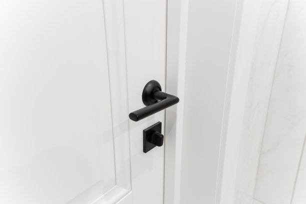 这是一张详细的特写照片，展示了安装在白色涂漆门上的黑色门把手，突显了其设计和在住宅环境中的功能性。图片下载