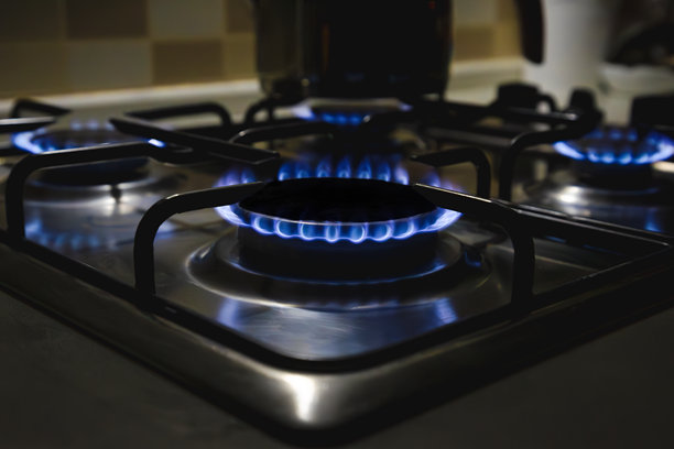 厨房煤气灶上燃烧的天然气，黑色背景下的燃气环灶面板特写照片图片下载