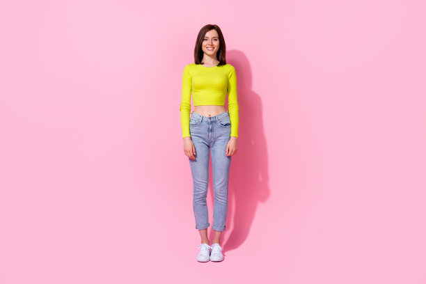 穿着青柠色衬衫的可爱搞笑女孩在粉色背景下微笑走路的全身照片图片下载