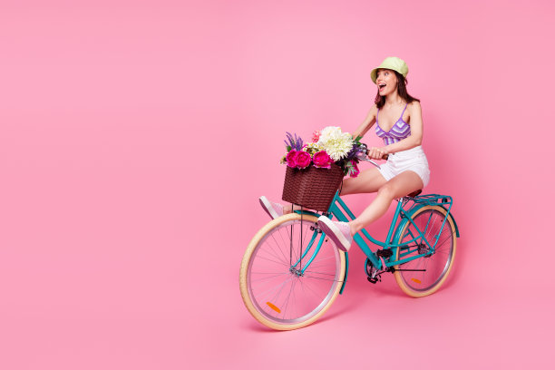 穿着紫色胸罩的惊讶女士骑自行车的全身照片，背景为粉色空白空间。图片下载