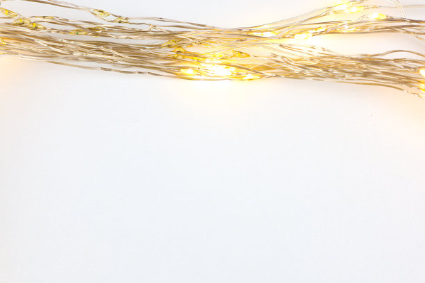 一条细长的金色新年花环躺在照片顶部的白色背景上。新年、圣诞节、假日的概念。图片下载