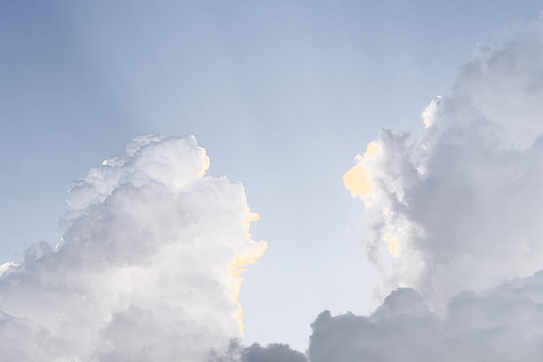 这是一张美丽的日落或日出照片，天空的主要颜色是明亮的橙色、黄色和红色。太阳部分被云层遮挡，使得天空看起来更加明亮和温暖。图片下载