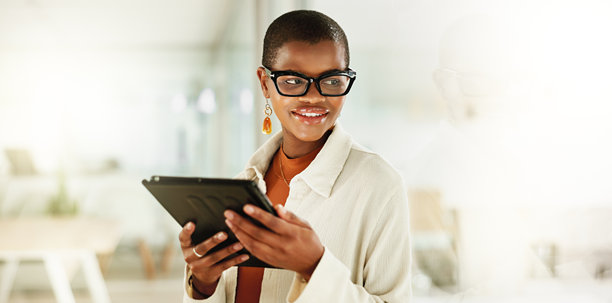 在玻璃办公室中，一位身穿黑色商务服装的女性正在编辑、构思和使用平板电脑，作为艺术出版设计师。她在工作场所中与快乐的插画师一起进行未来规划和愿景，为在线平面设计而努力。图片下载