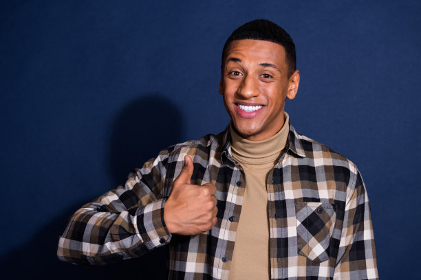 穿着时尚格子衣服的迷人年轻男子在深蓝色背景下竖起大拇指的照片肖像图片下载