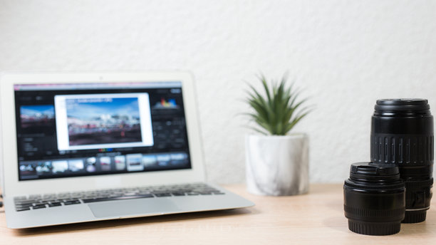 摄影师在笔记本电脑上编辑照片，桌上放着镜头图片下载