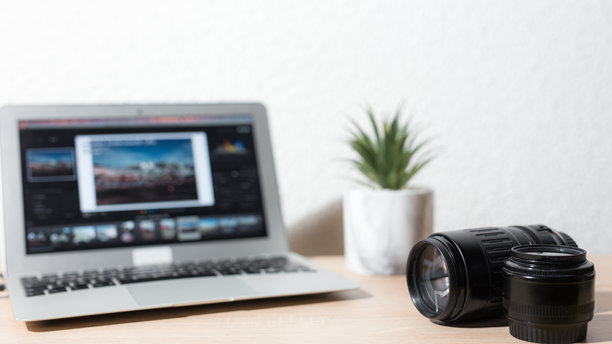 摄影师在笔记本电脑上编辑照片，桌上放着相机镜头图片下载