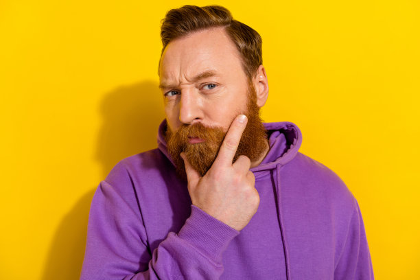 阳光明媚的黄色背景下，阳刚的男子在理发店里思考新的发型的特写照片图片下载