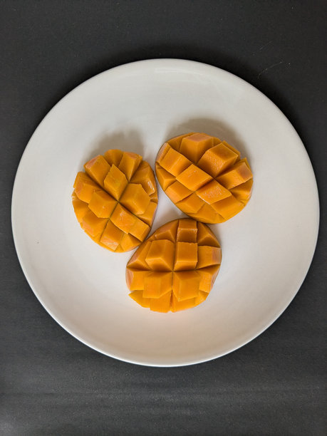 新鲜甜美的黄色芒果特写照片，摆放在盘子上图片下载