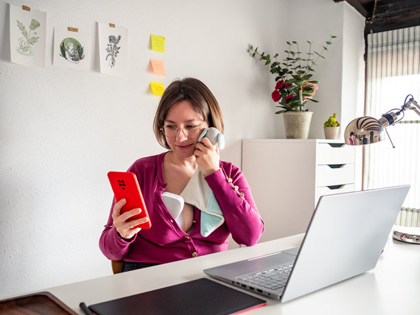 女性在办公室使用吸奶器，同时查看她宝宝的照片图片下载