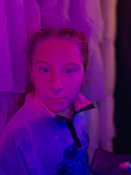 年轻快乐自信的女孩在自制的照片亭中，紫色和蓝色的灯光照耀着她。图片下载