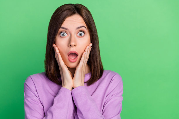 特写照片：年轻有趣的迷人女孩因便宜的衣服促销而感到震惊，背景为绿色。图片下载